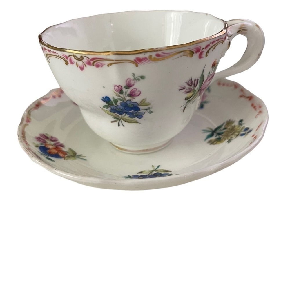 Teacup and saucer, unmarked with flowers and gold trim.